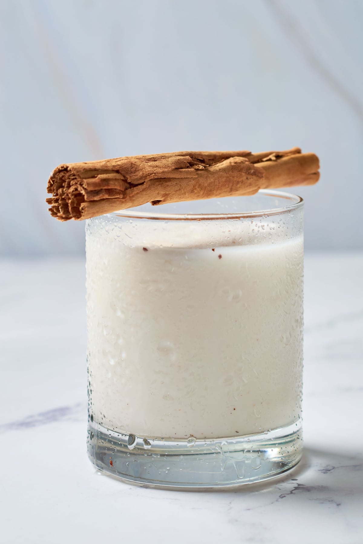 A glass of horchata with cinnamon sticks placed on top.