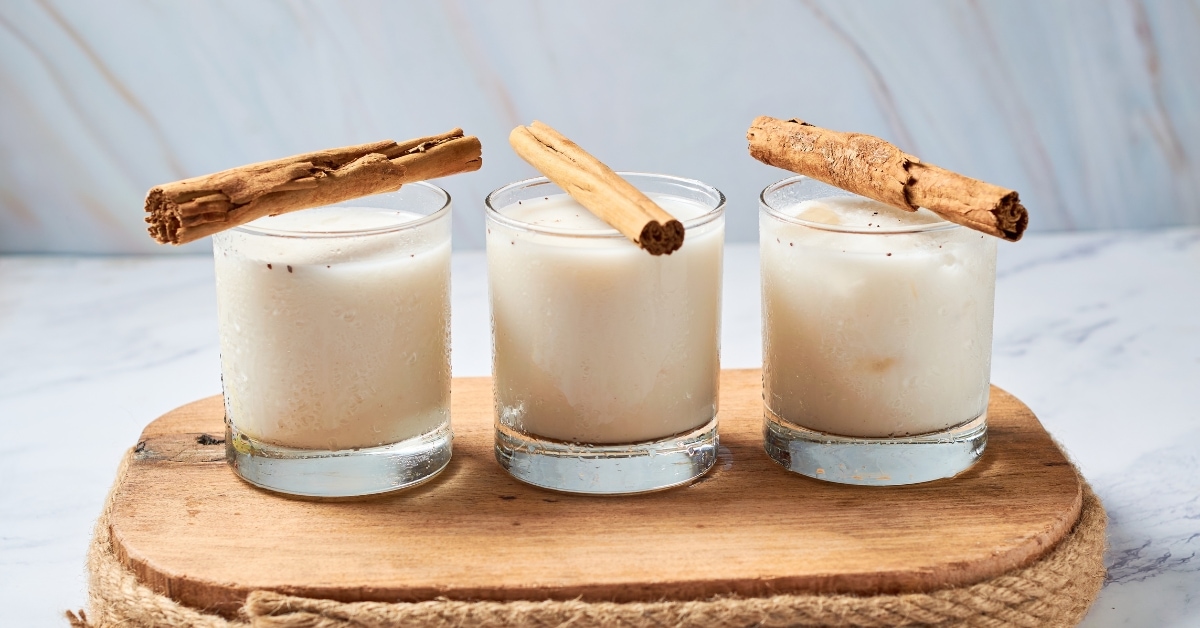 A wooden tray with three glasses of mexican horchata, perfectly arranged for a refreshing and wholesome beverage.
