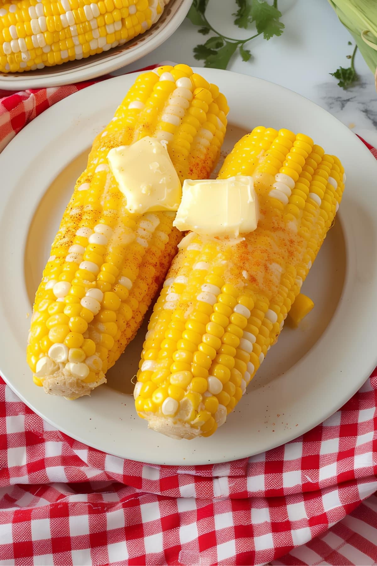 Homemade microwave corn on the cob topped with butter on a white plate