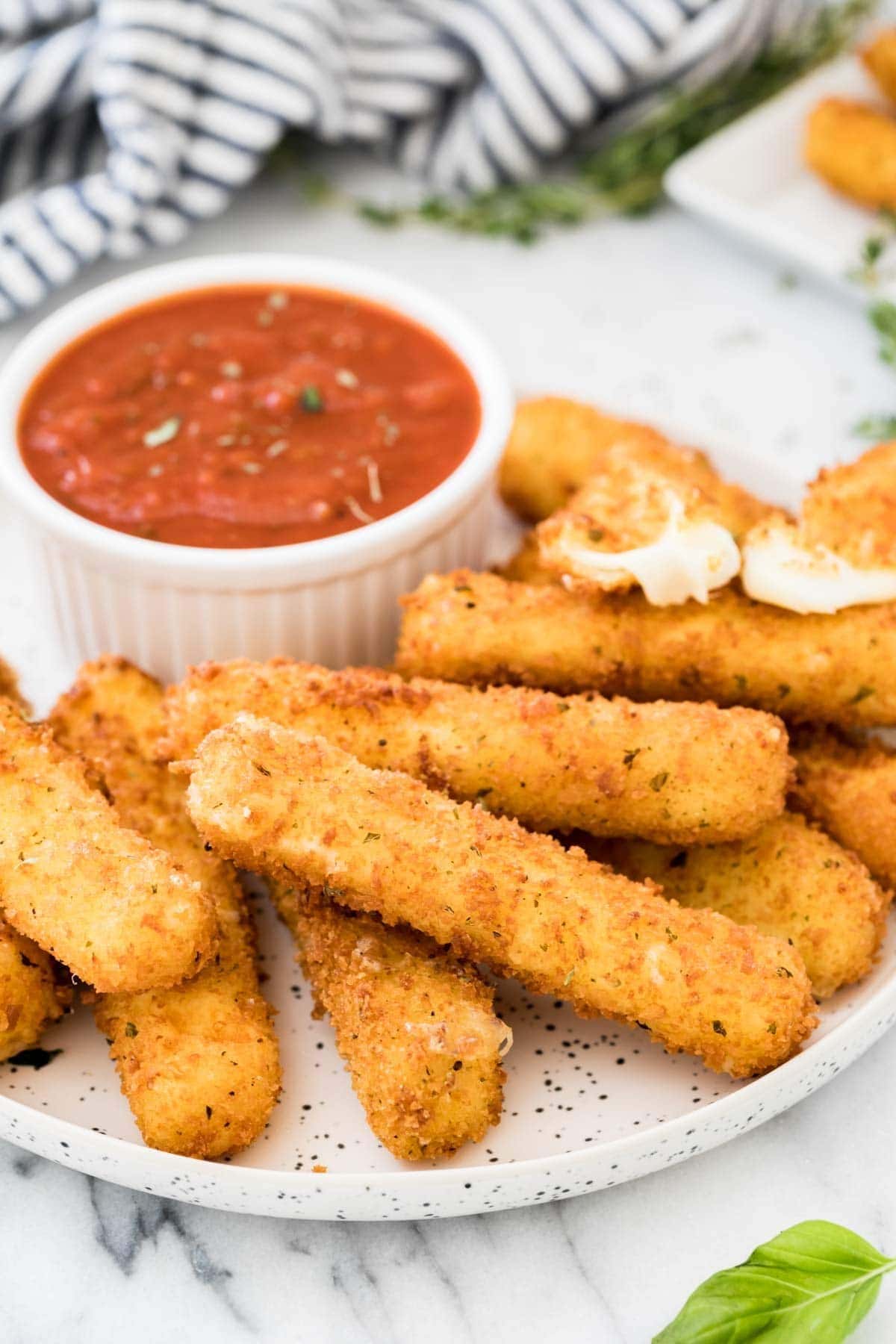 A platter of breaded mozzarella sticks served with a dipping sauce.