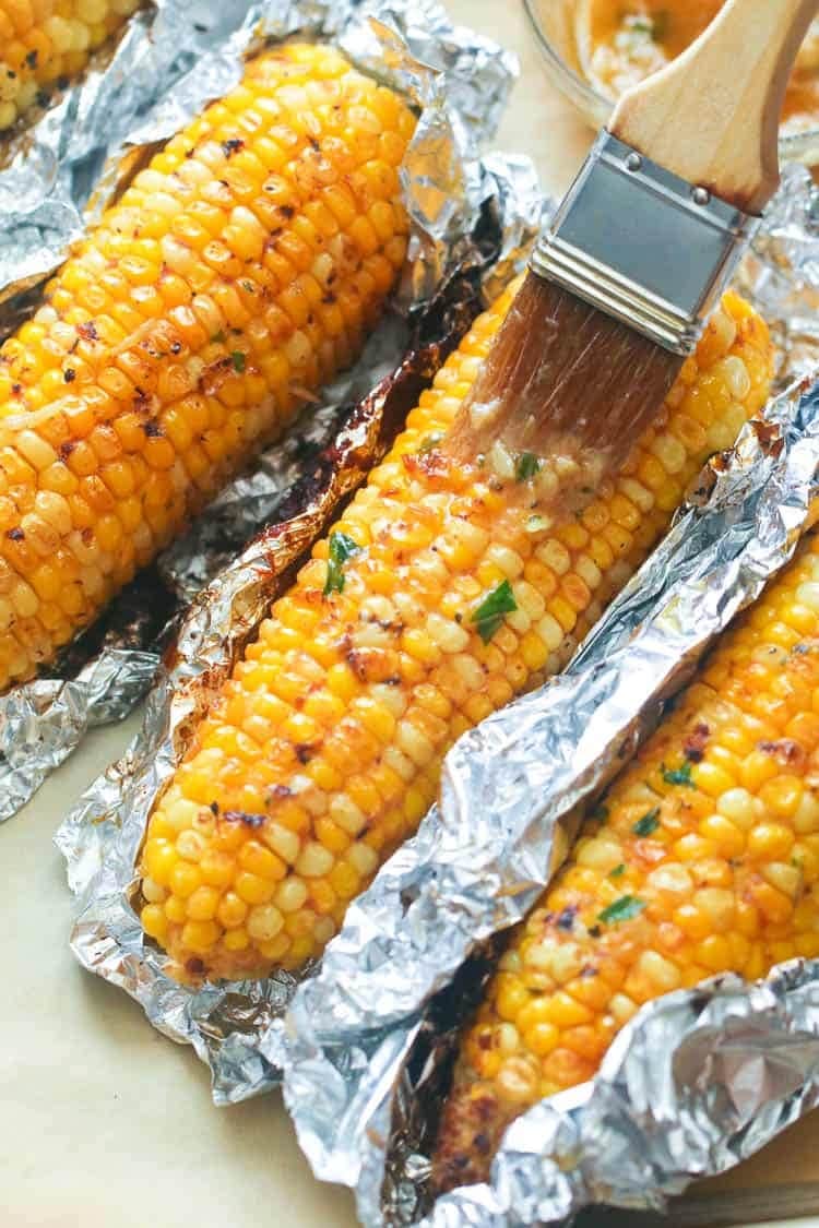 Butter spread over roasted corn wrapped in an aluminum foil. 