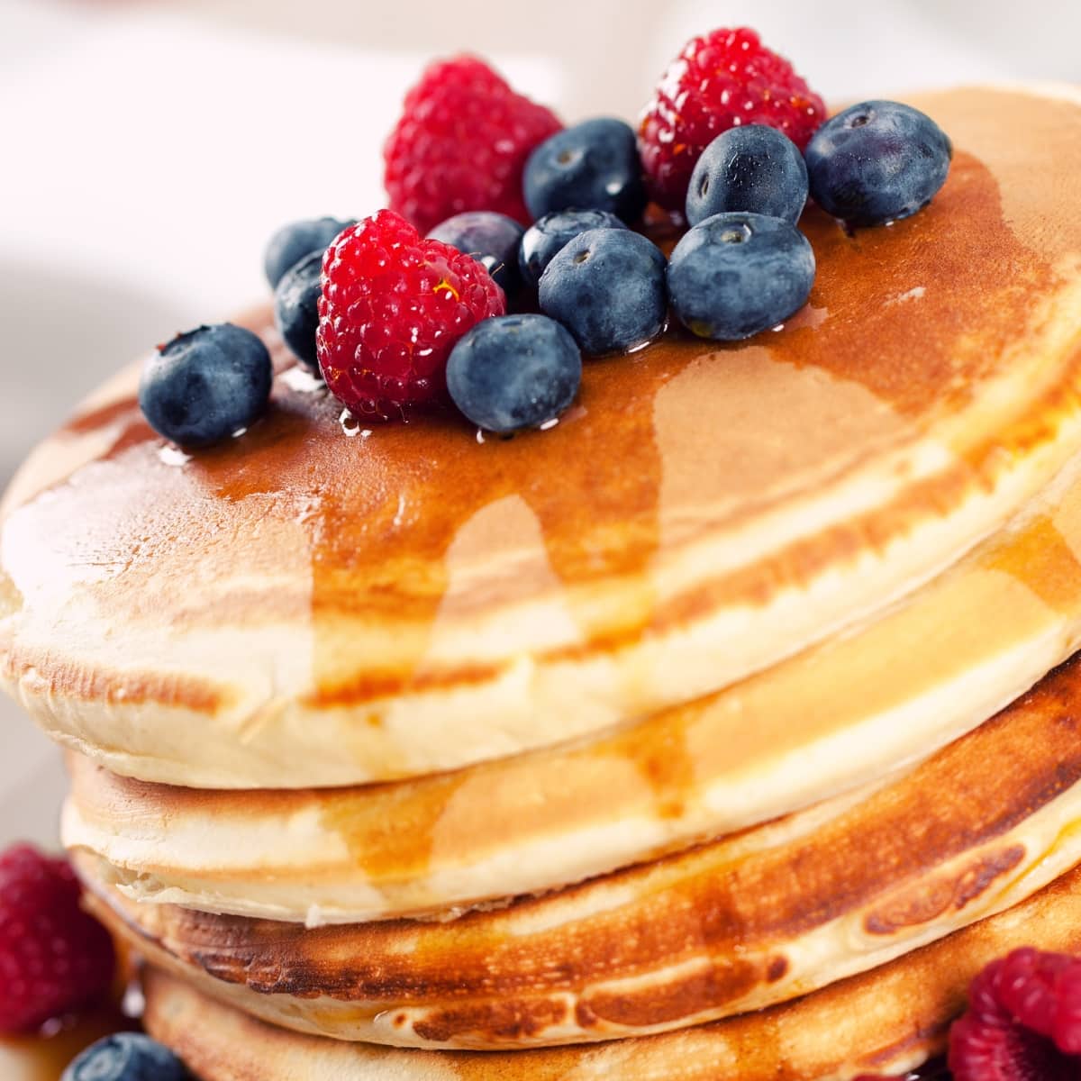 Fluffy Bisquick pancakes stack on a plate topped with blueberries and raspberries.