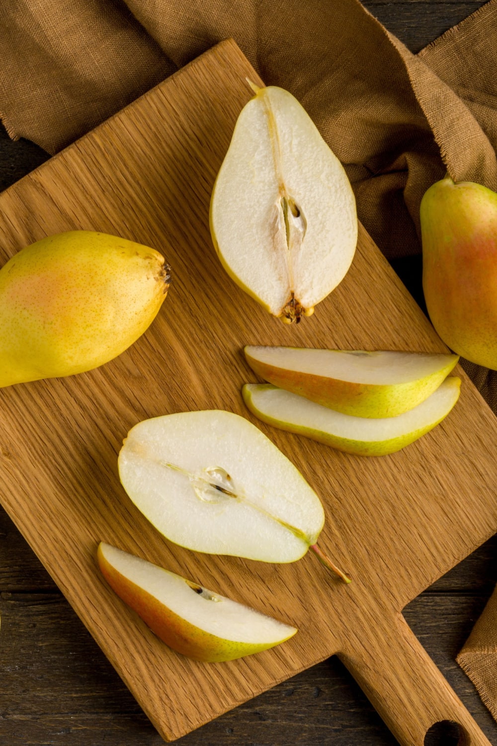 Pears sliced in halves on top of a wooden board.