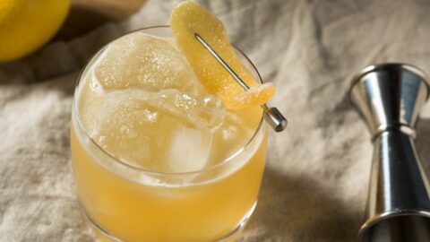 Penicillin cocktail on a glass filled with ice garnished with lemon wheel.