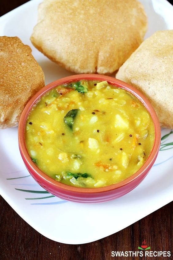 Poori curry on a small red bowl served with puff bread on a plate. 