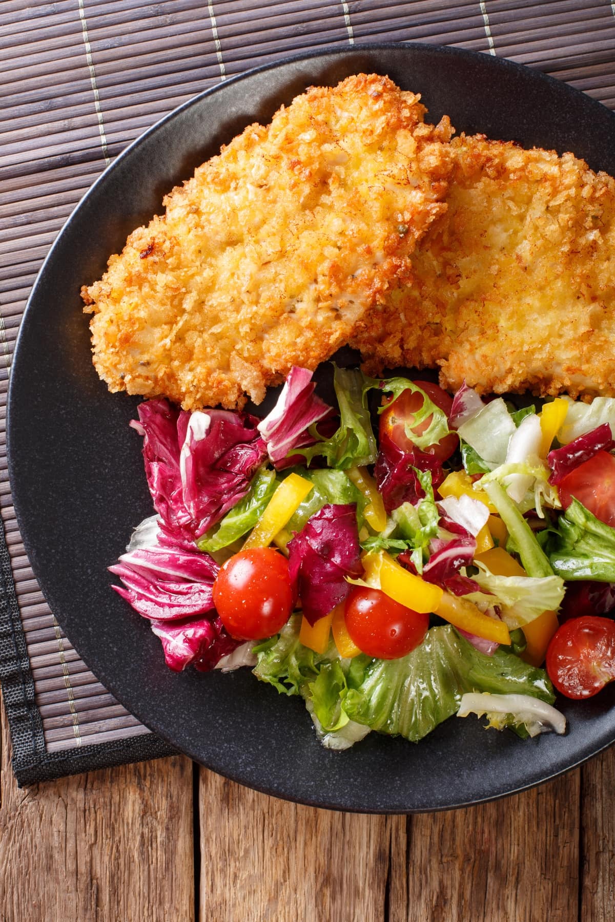 A plate of food with a fresh vegetable salad and a succulent chicken schnitzel. A delicious and healthy meal option