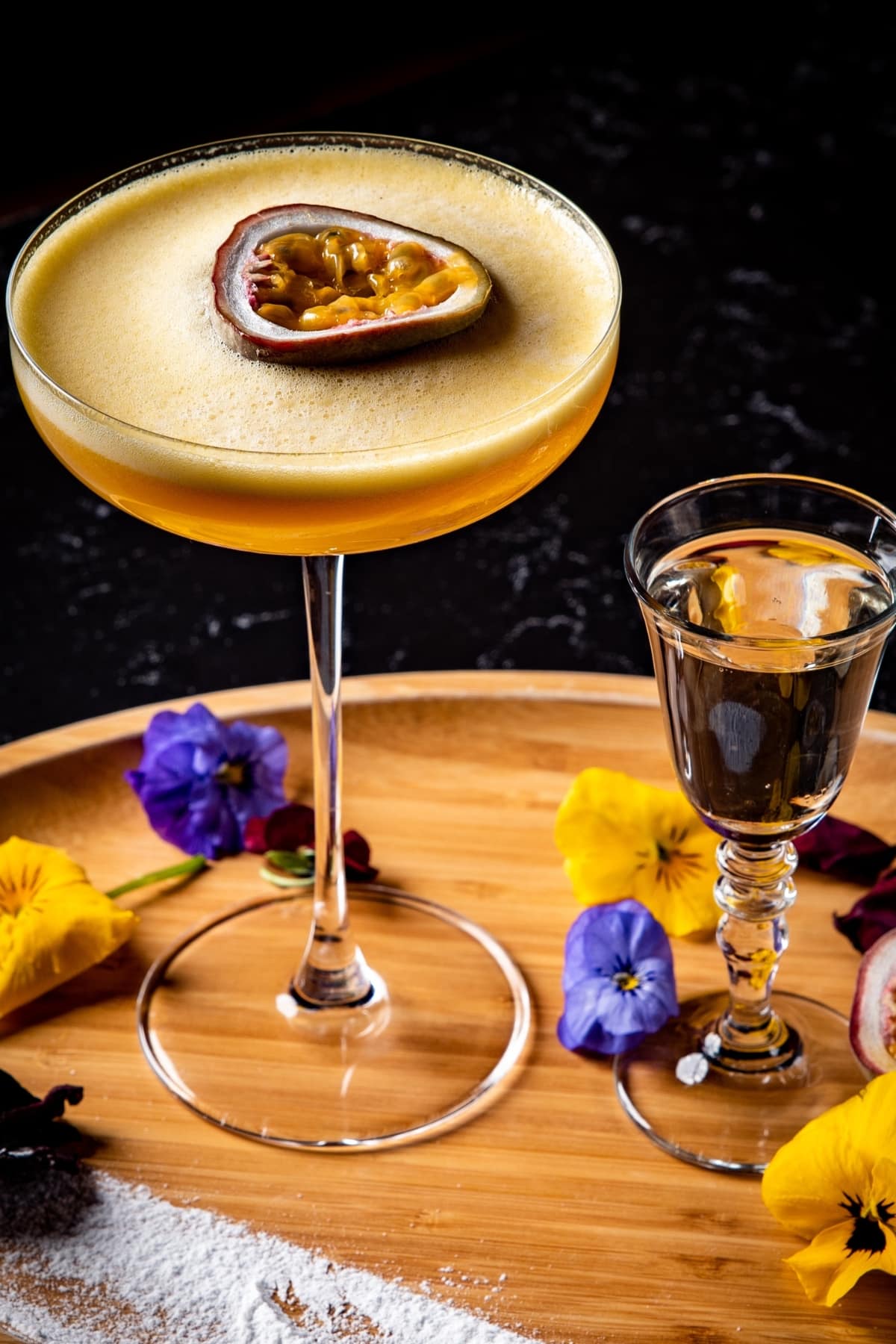 Porn star martini and Prosecco garnished with passion fruit served on a wooden tray.
