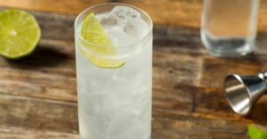 Sparkling Ranch water on a highball glass filled with ice on a wooden table.