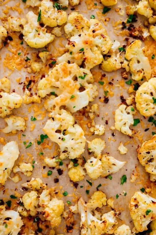 Roasted cauliflower sprinkled with spices and chopped hers on a sheet pan.