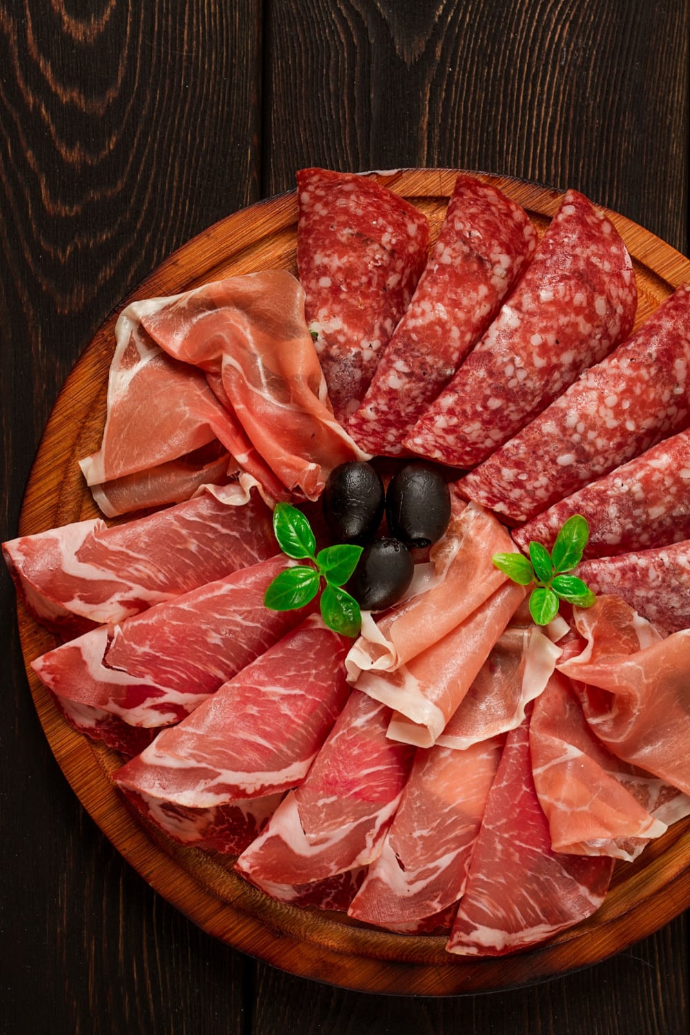 A wooden platter of salami and prosciutto. 
