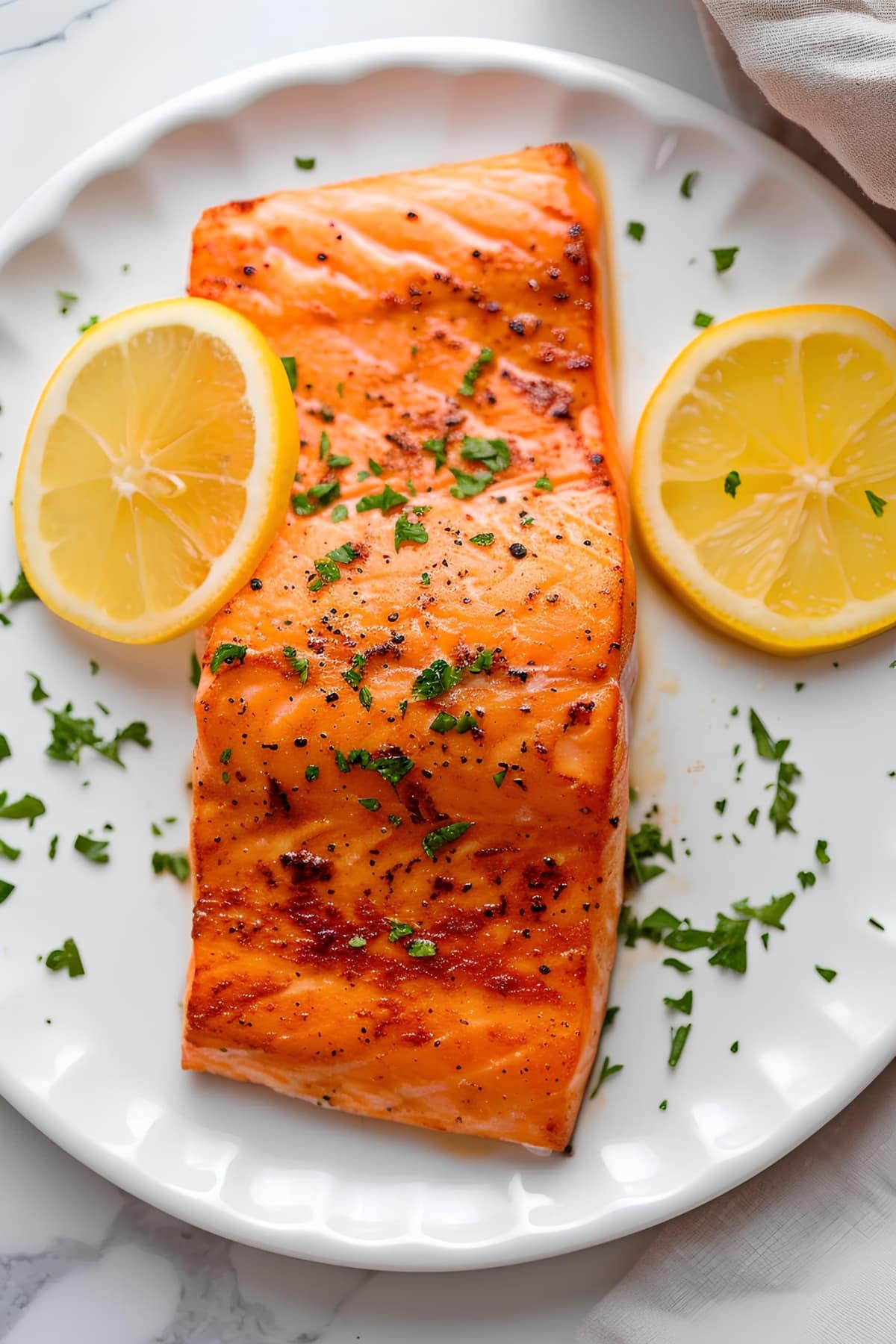 Tender and juicy salmon fillet with lemon wedges in a white plate