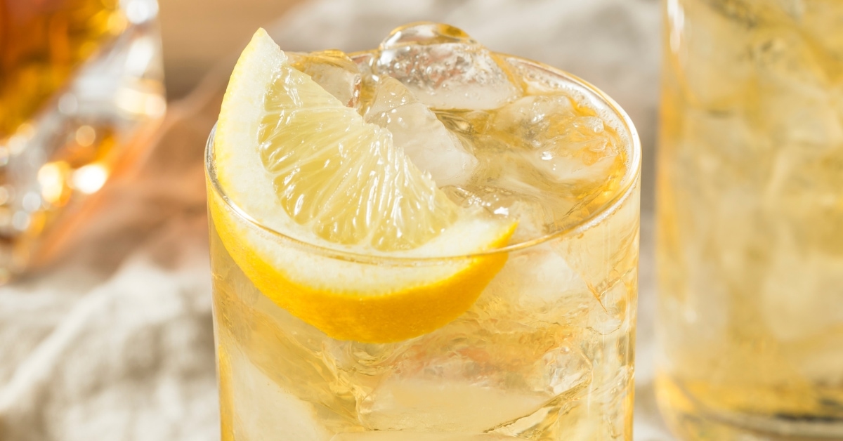 Seven and seven cocktail garnished with sliced lemon served on highball glasses filled with cracked ice.
