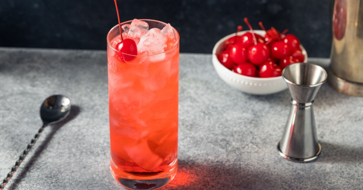 Shirley temple drink filled with ice garnished with fresh cherries.