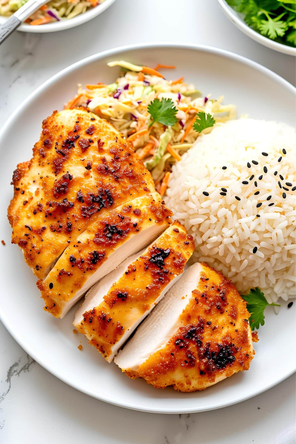 Tender and juicy chicken breast served with coleslaw and white rice in a plate