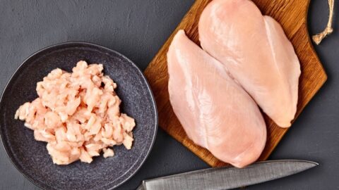 Sliced chicken meat in chopping board and black plate.