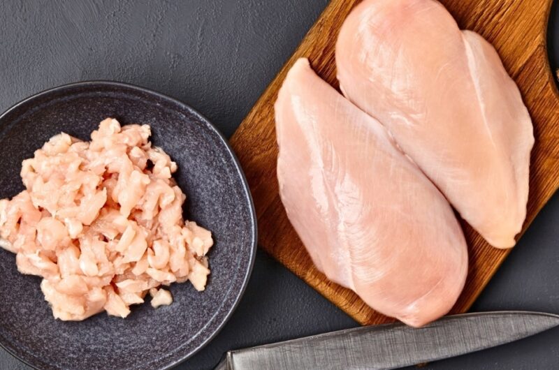 Sliced chicken meat in chopping board and black plate.