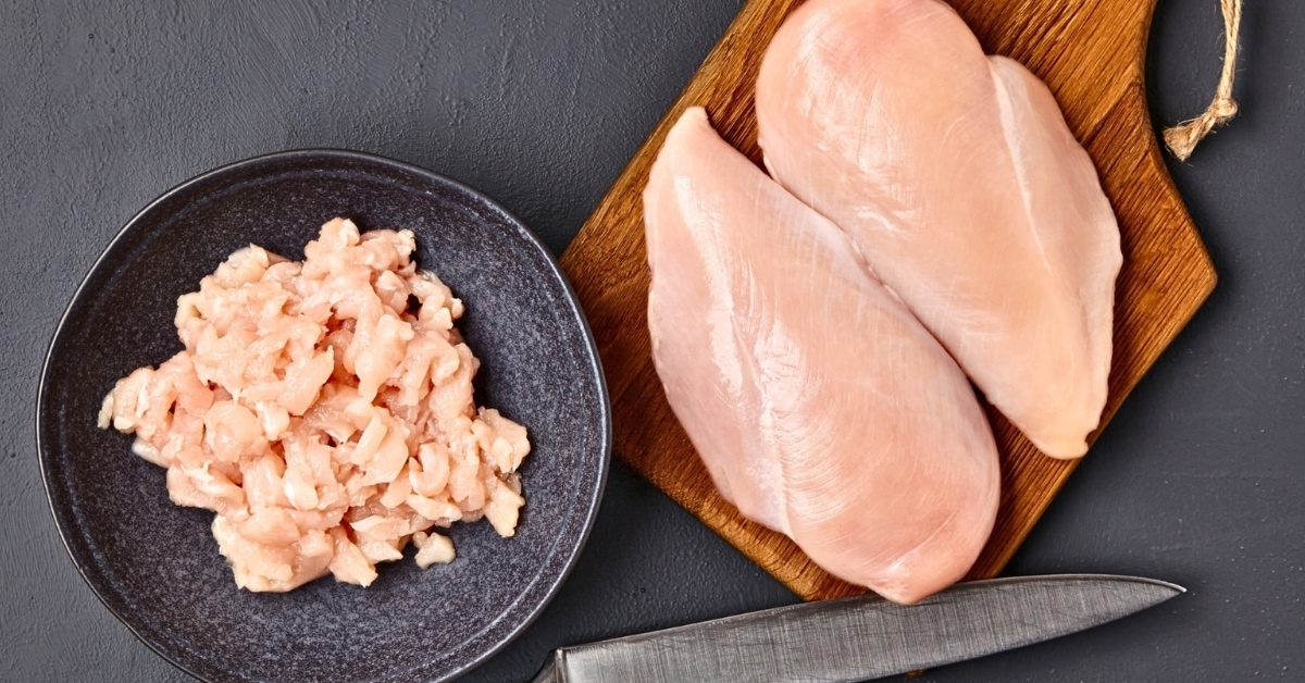 Sliced chicken meat in chopping board and black plate.
