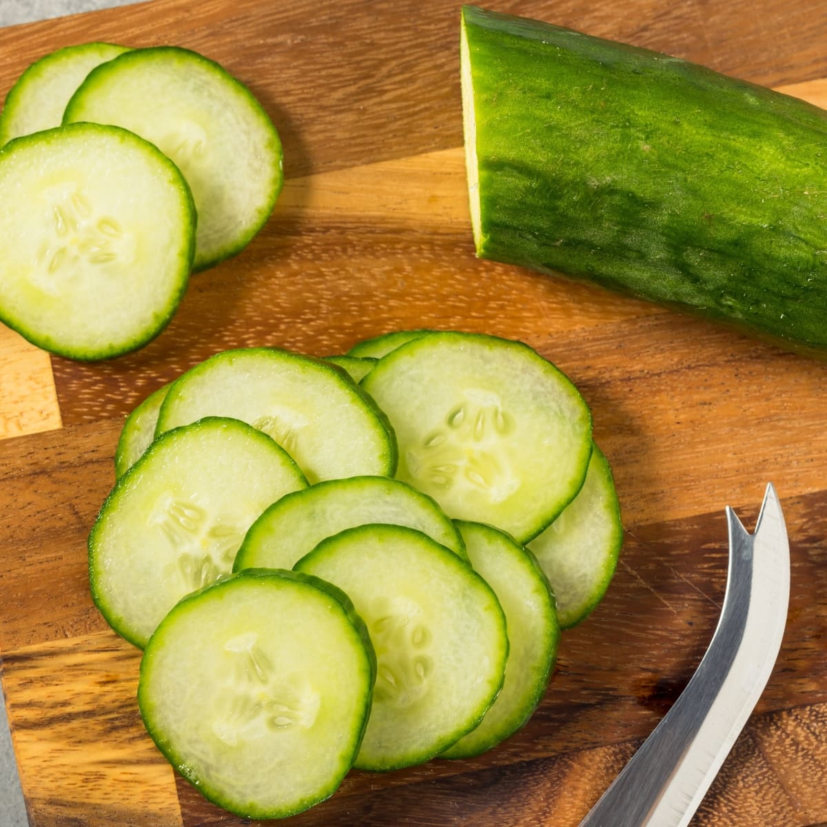 Sliced cucumber on a wooden chopping board. 