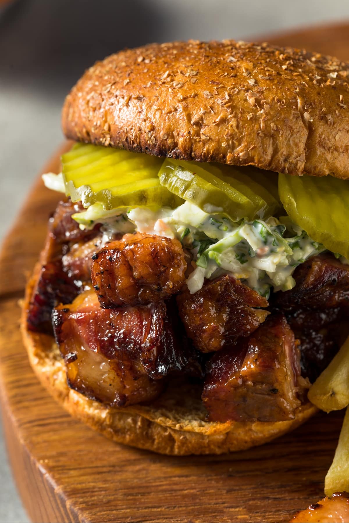 A close up of burnt end sandwich with creamy coleslaw and pickles