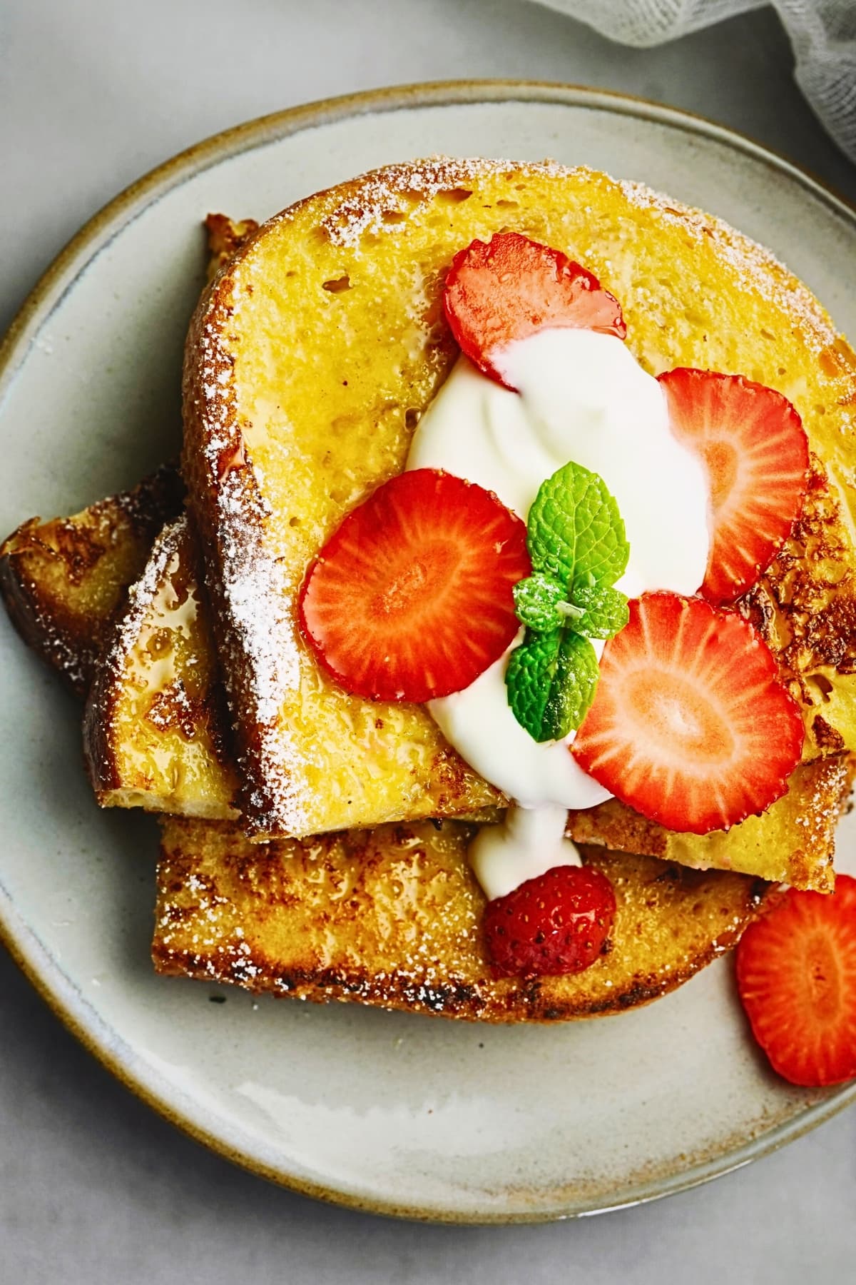 Sourdough French toast topped with sliced strawberries and whipped cream.