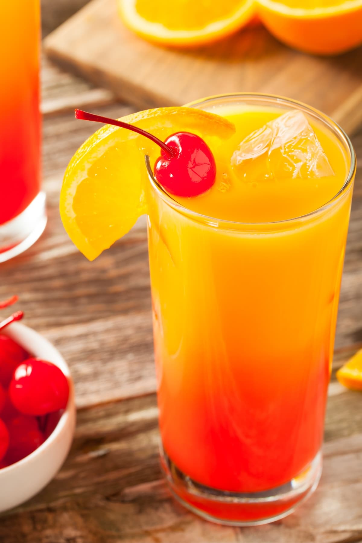 Tequila Sunrise cocktail in a glass garnish with a slice of orange and cherry. 