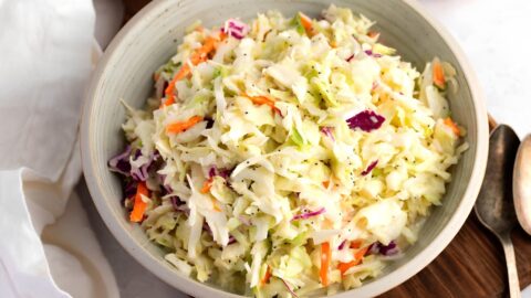 Coleslaw mix with dressing and poppy seeds served on a bowl.