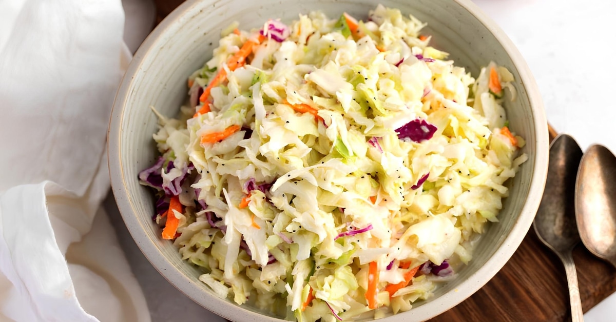 Coleslaw mix with dressing and poppy seeds served on a bowl.