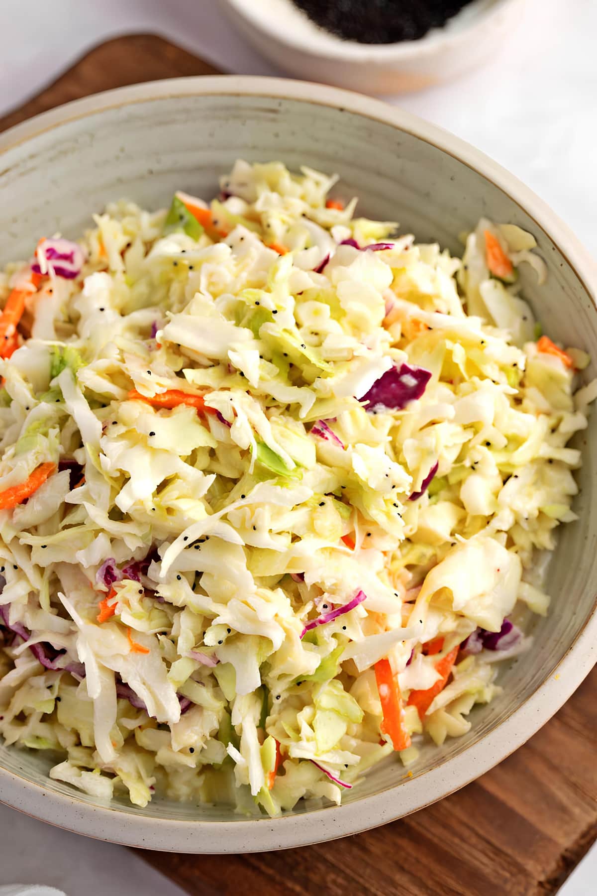 Coleslaw mix with dressing and poppy seeds on bowl.