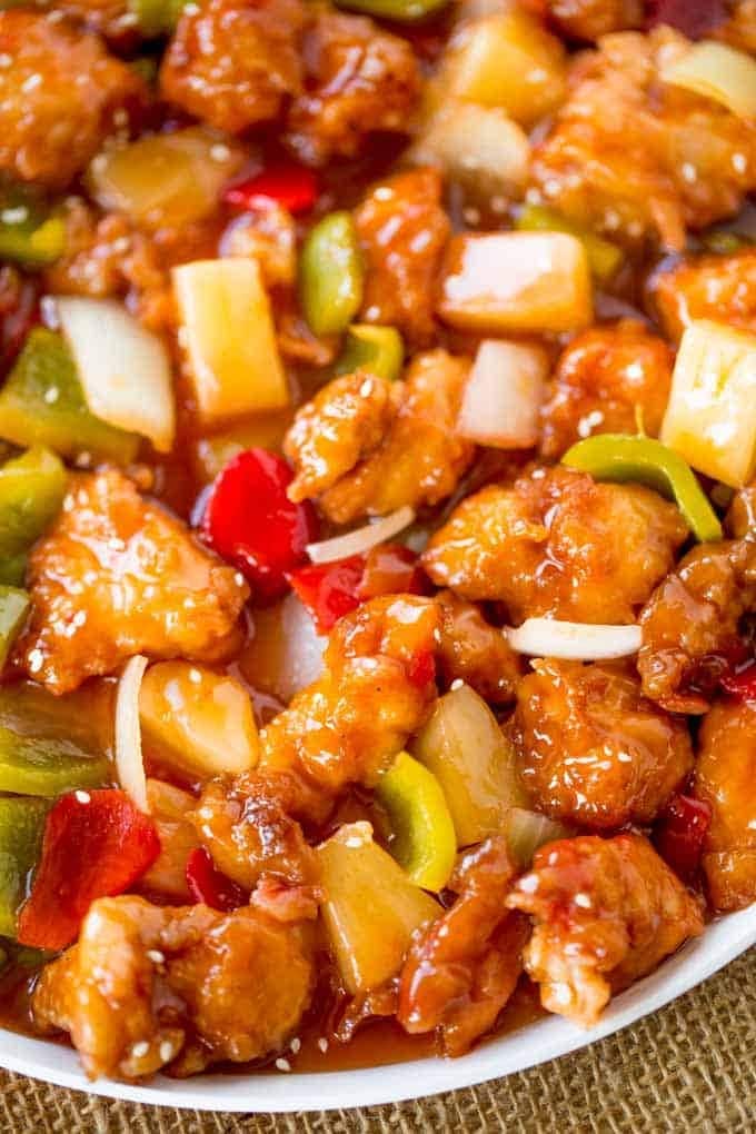 Sweet and sour chicken with pineapple, and bell peppers served on a white plate. 