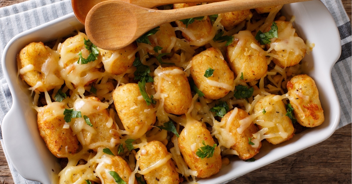 Tater tots casserole on a baking dish with wooden spoon.