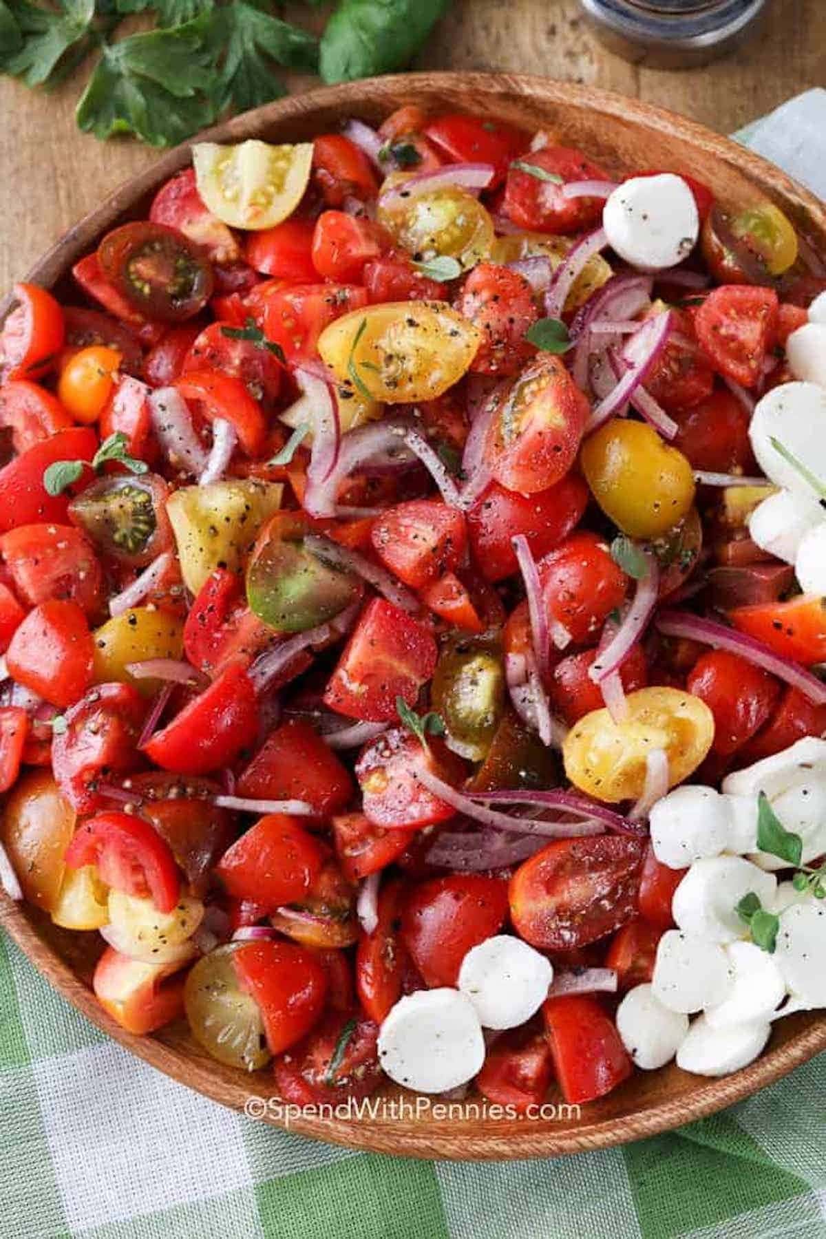 A bowl of tomato salad with red onions and herbs 