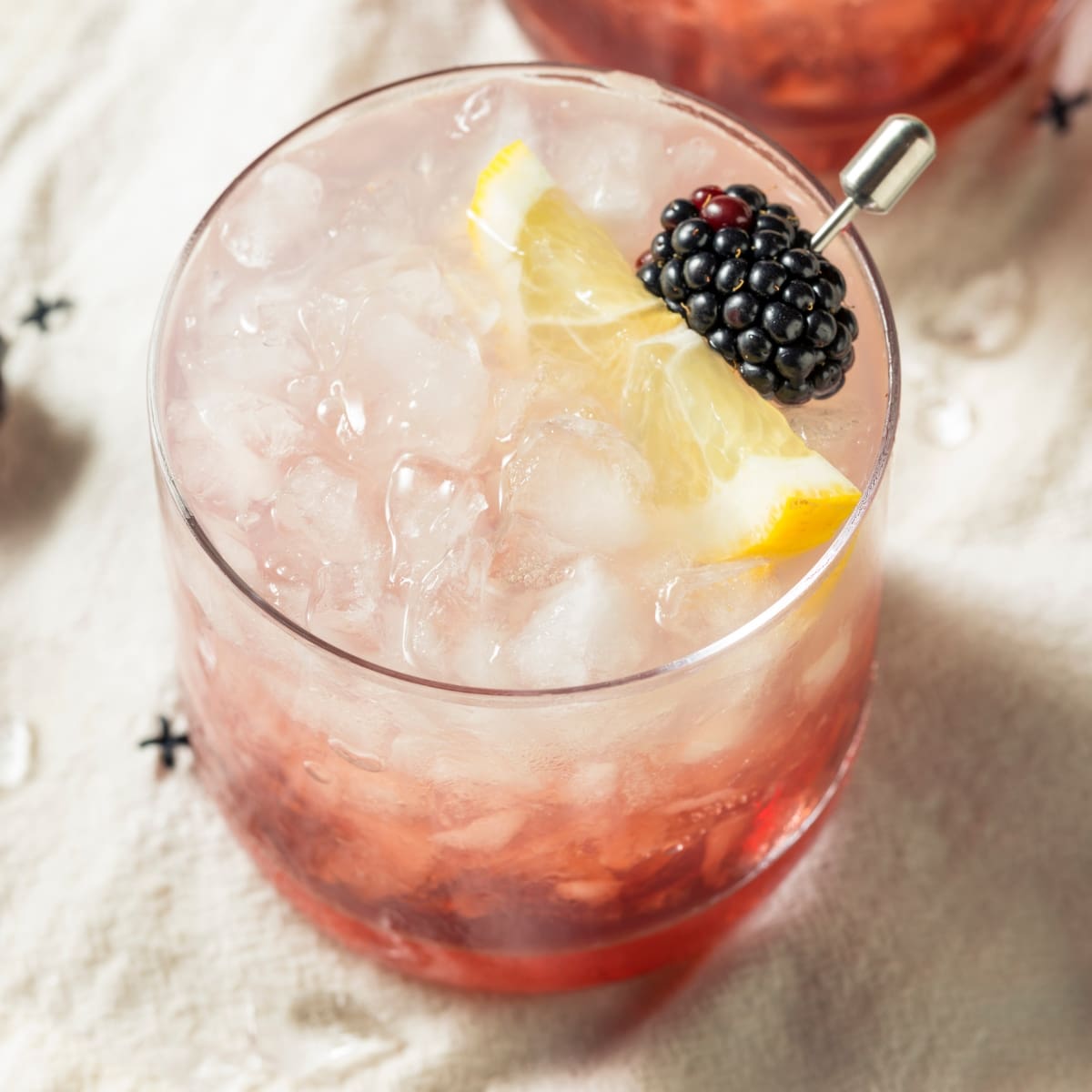 Top view of Bramble cocktail served in a glass filled with crushed ice garnished with blackberries and lemon slice. 