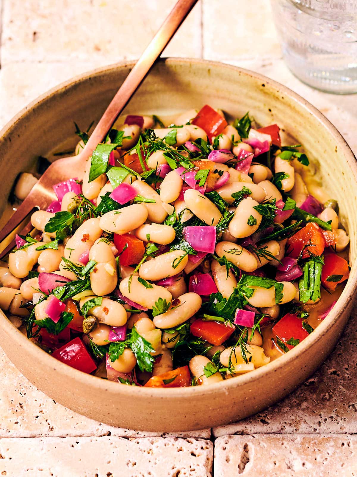 Bean salad on a wooden bowl with white cannellini beans, lemon, bell pepper and dill.