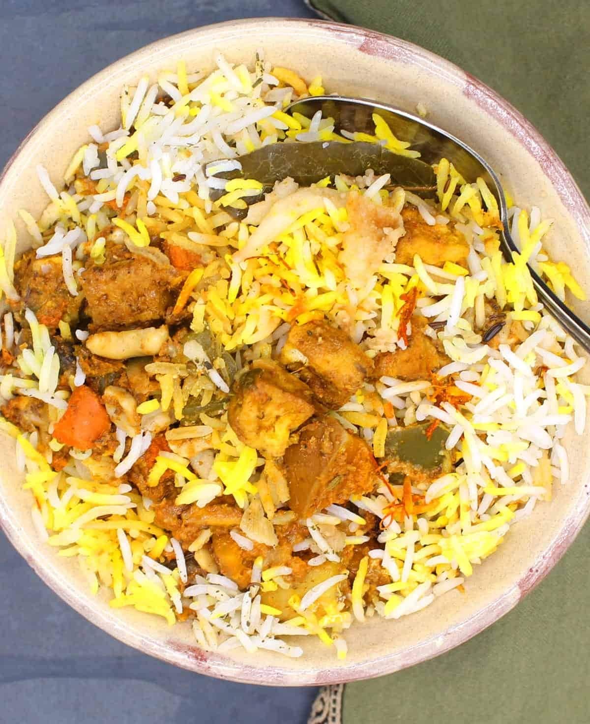 Vegetable biryani with layers of long-grain basmati rice and a rich masala sauce on a bowl. 