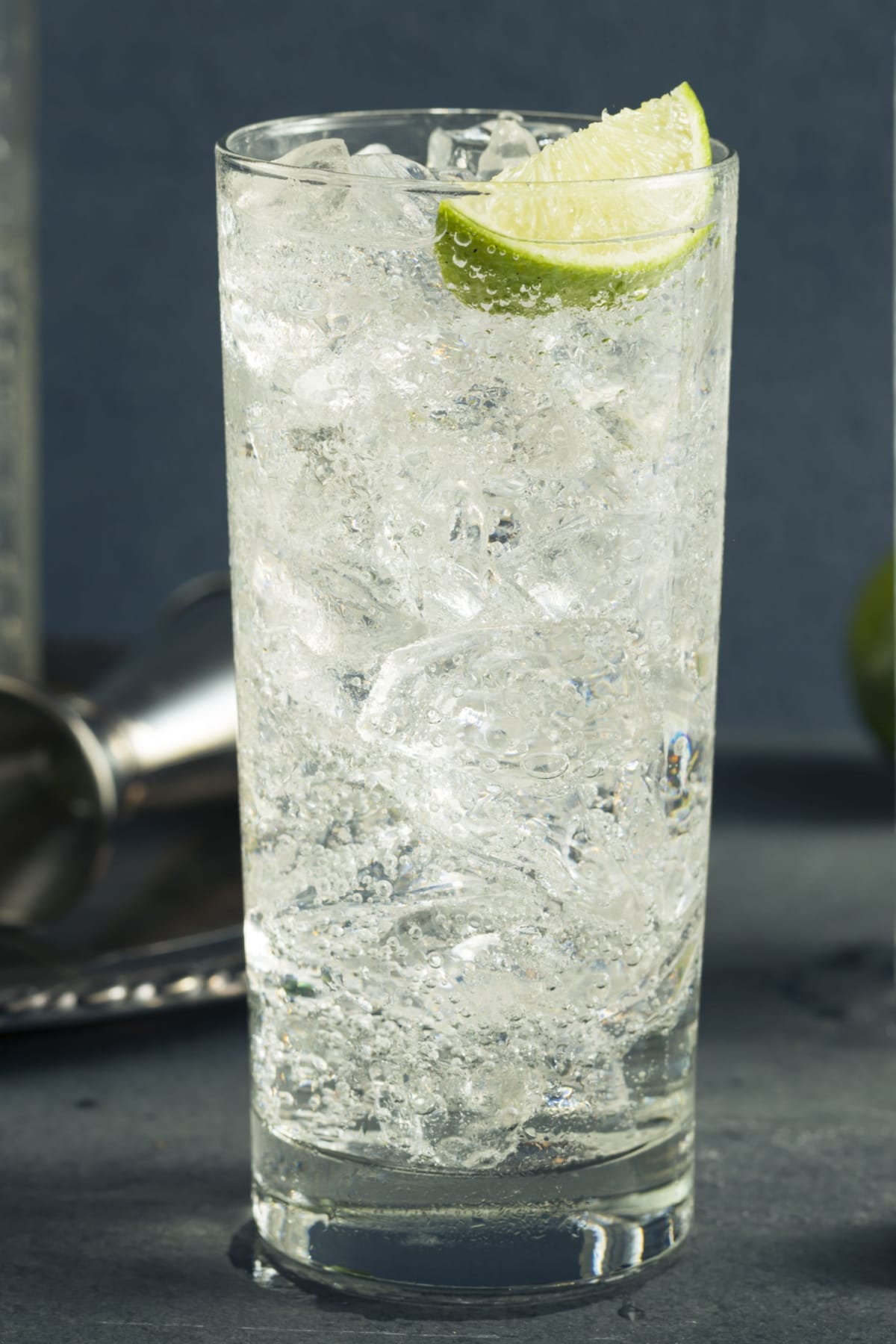 Tall glass of vodka soda filled with ice garnished with lime slice. 