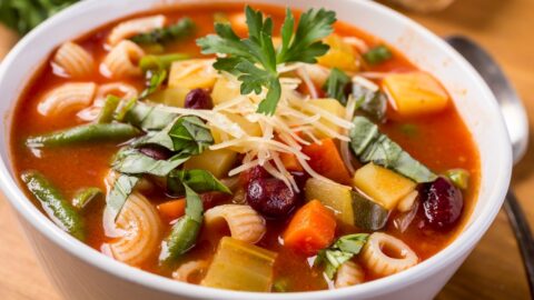 A bowl of minestrone soup with pasta, veggies, and cheese. A comforting and nutritious meal option