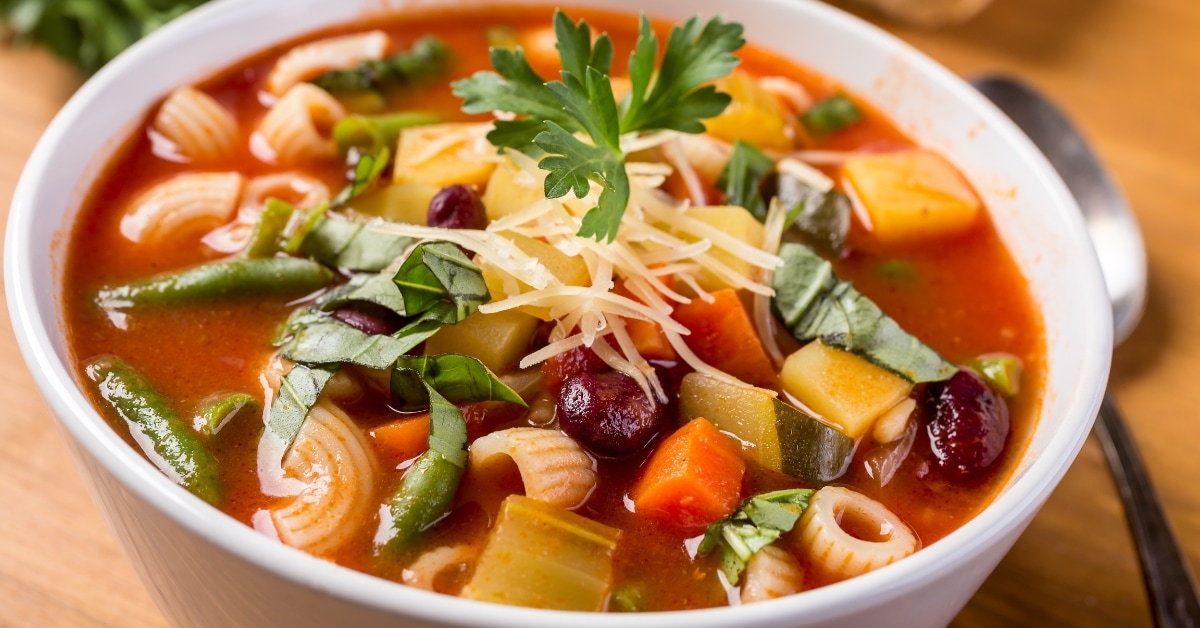 A bowl of minestrone soup with pasta, veggies, and cheese. A comforting and nutritious meal option