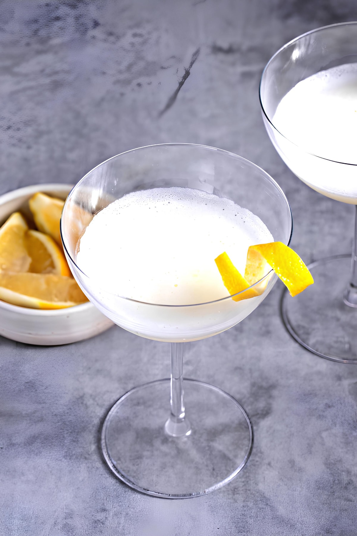 White lady cocktails served on wine glasses garnished with lemon twist. 