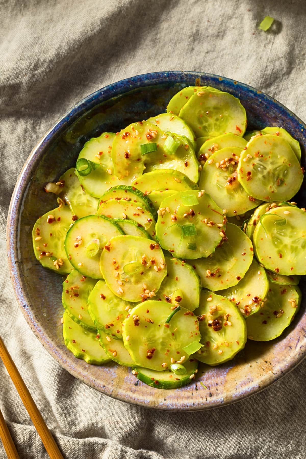 Wooden bowl of thinly sliced Asian cucumber salad.