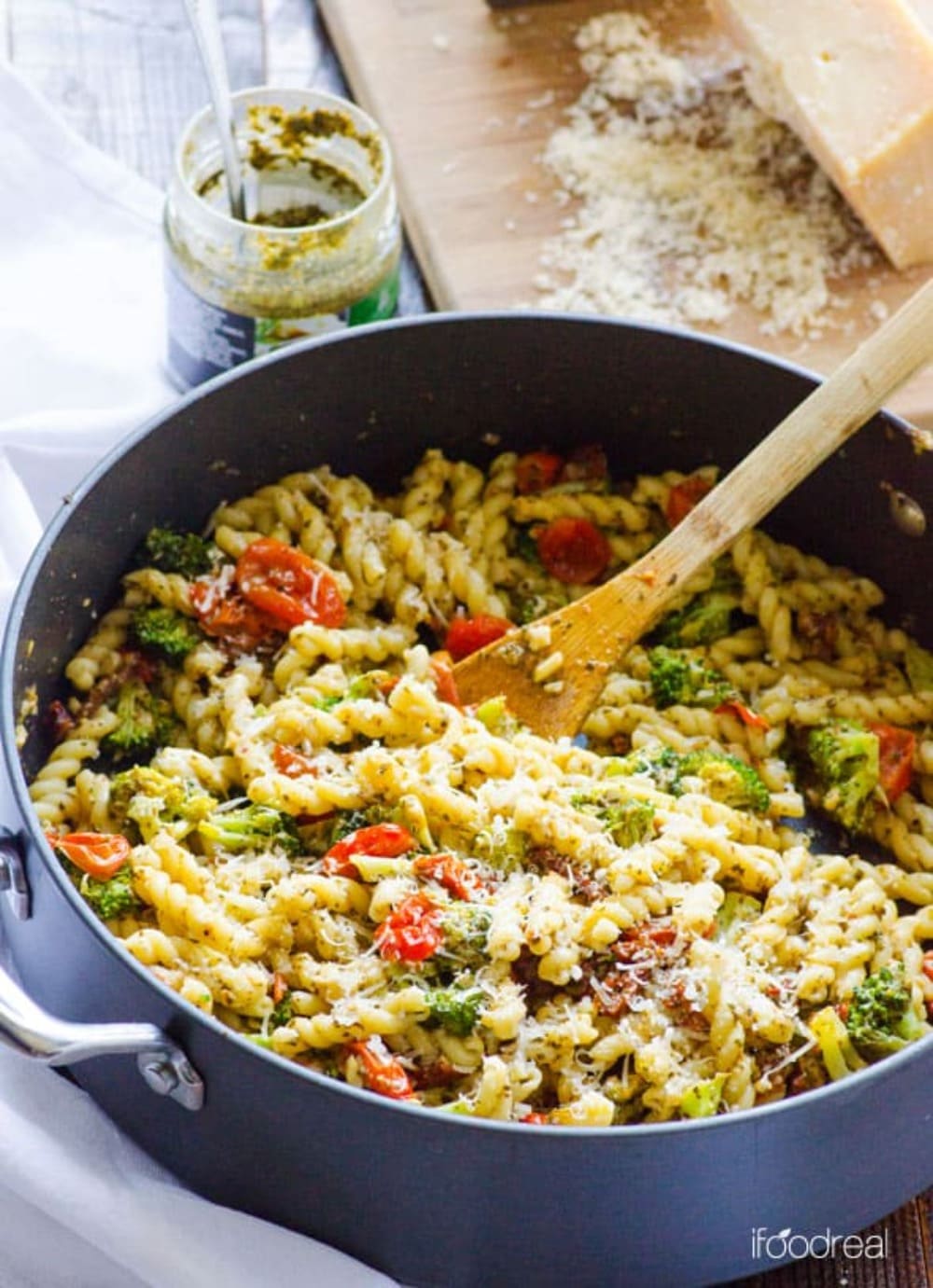 Healthy pesto pasta with broccoli and tomatoes in a pot with parmesan cheese