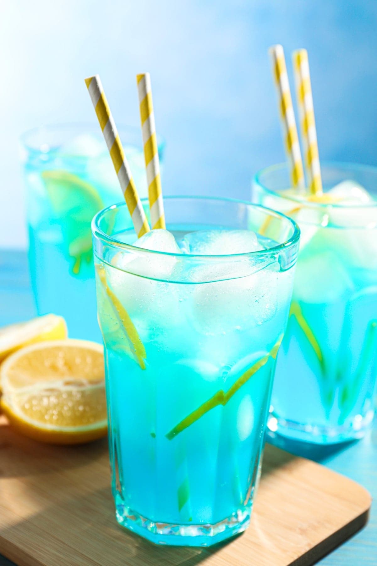 Icy Blue Lagoon Cocktails on highball glasses with yellow striped straws