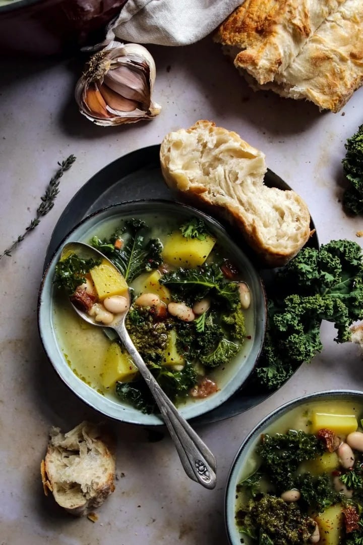 Two bowls of healthy, vegan zuppa Toscana soup with kale, beans, and potatoes