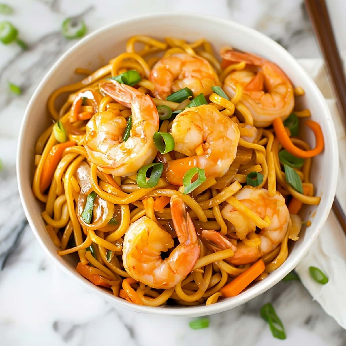 Savory shrimp lo mein with green onions and carrots in a white bowl