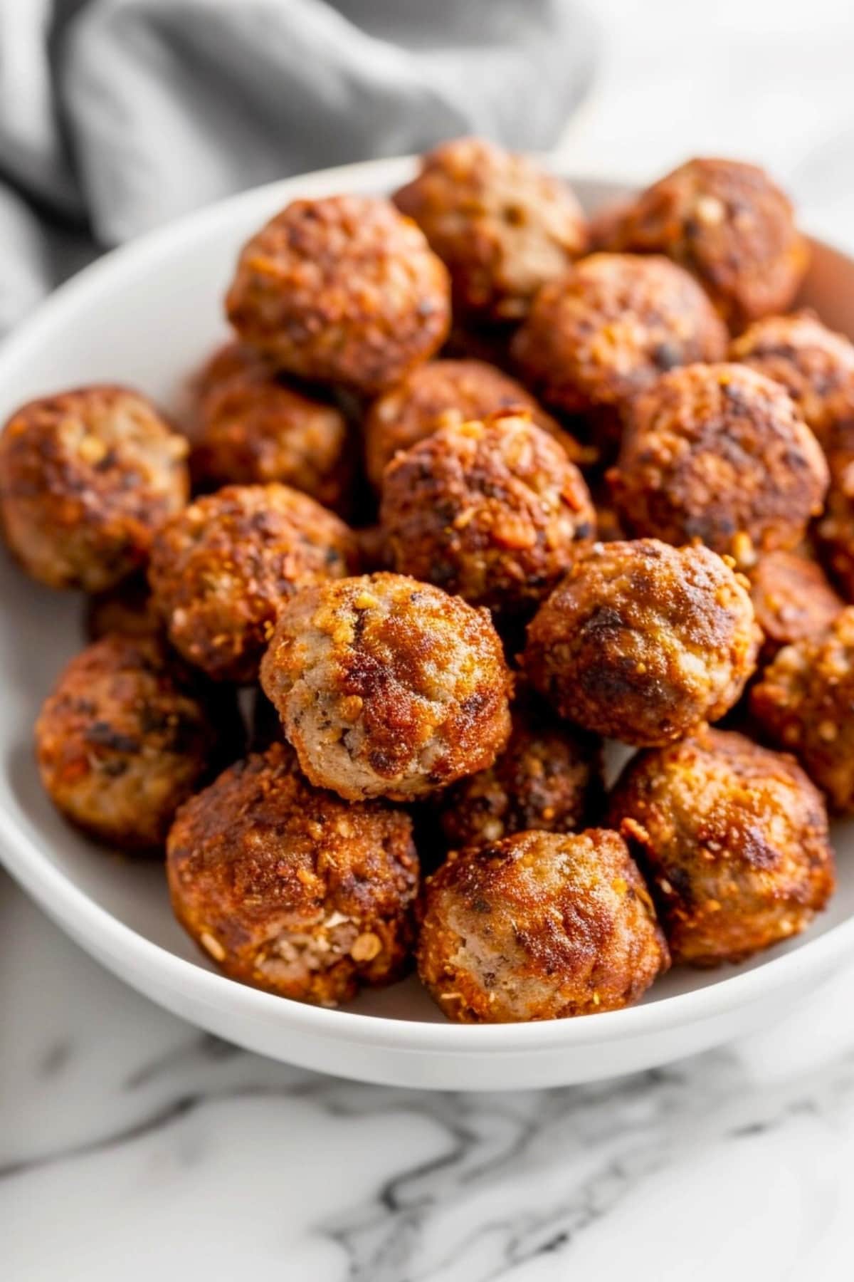 Bunch of meatballs in a white bowl.