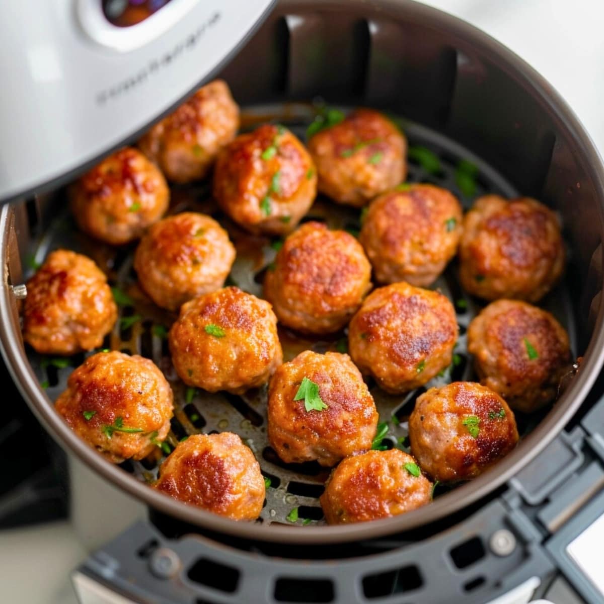 Meatballs arranged inside an air fryer.