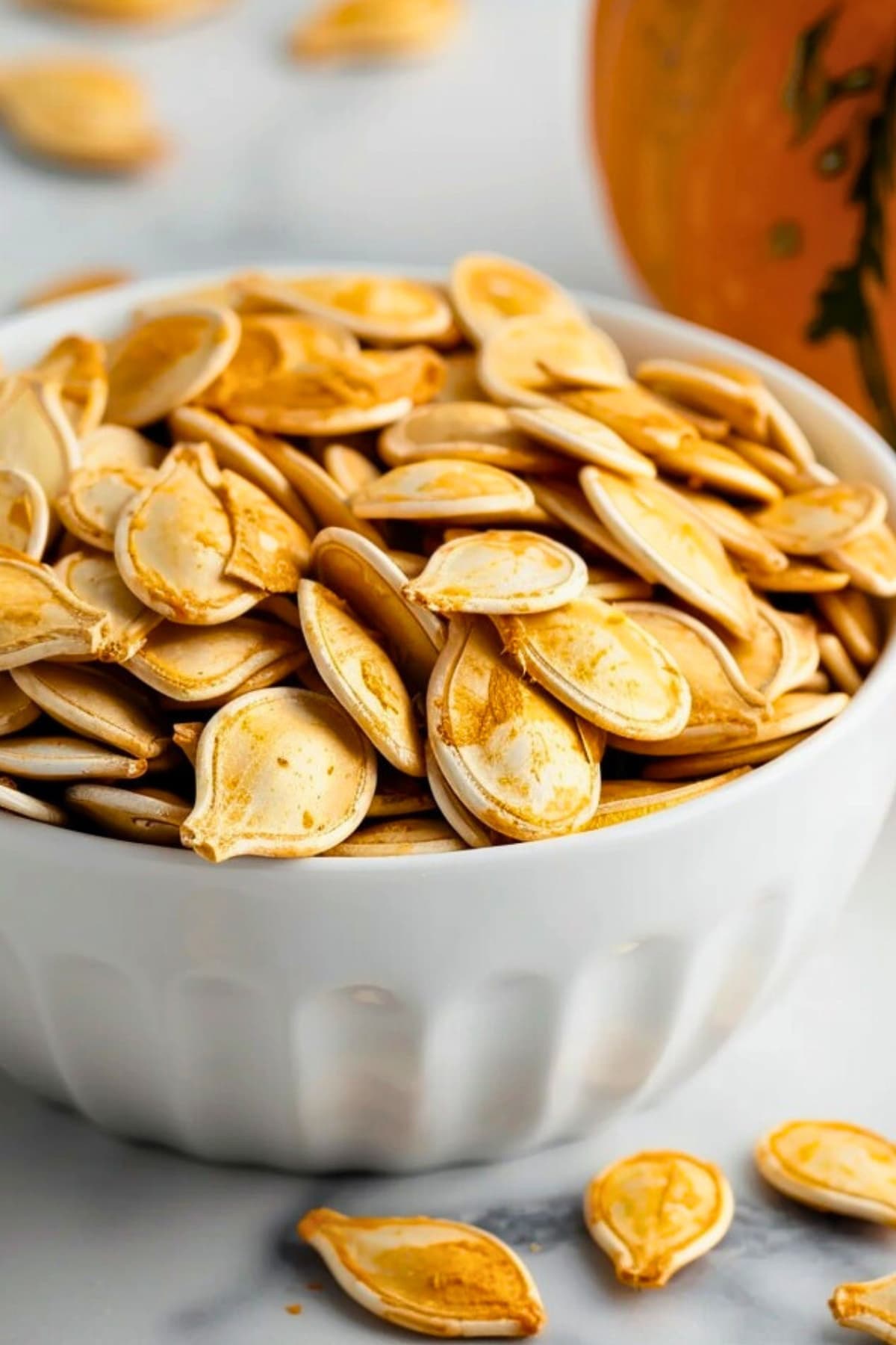 Bunch of air fried pumpkin seeds in a white bowl.