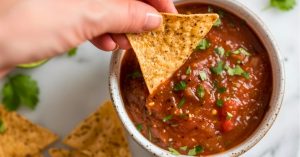 A piece of air fried tortilla chips dipped in salsa.