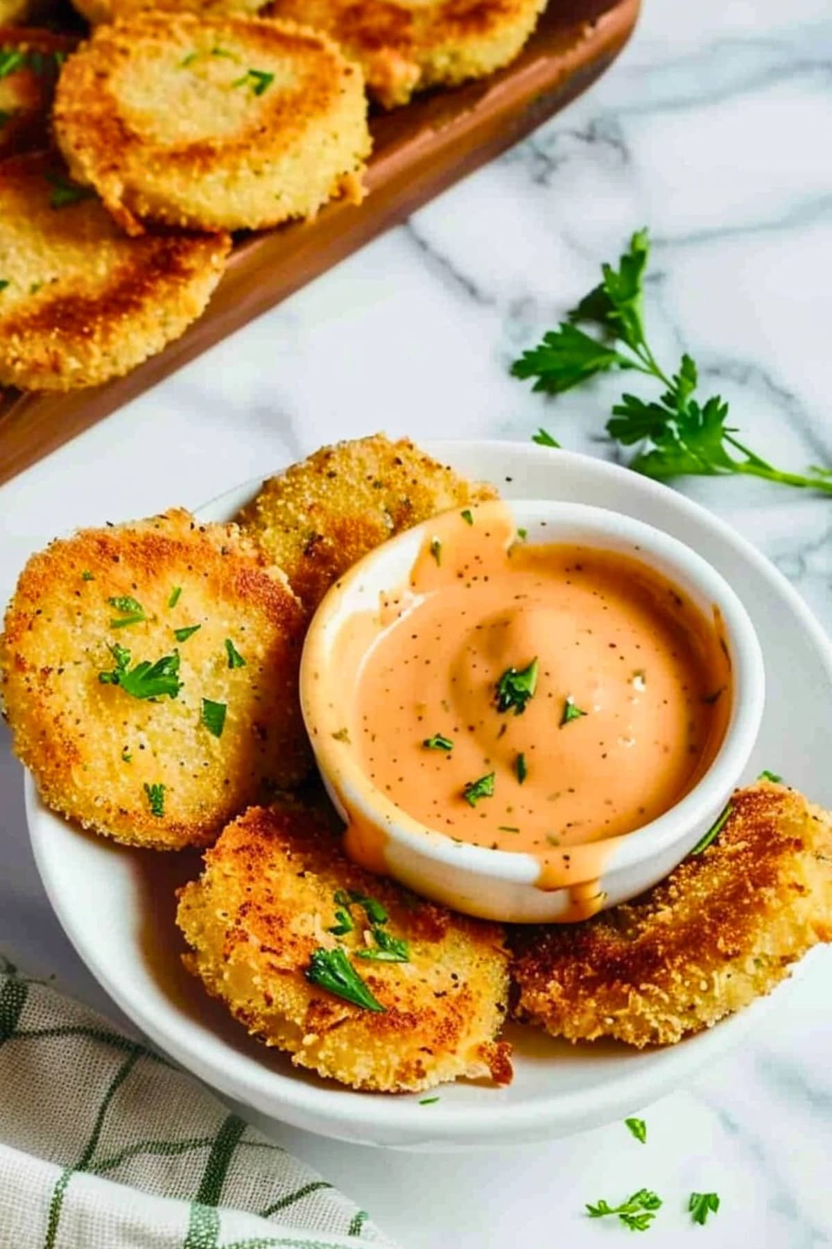 Crispy Air Fryer Fried Green Tomatoes on plate with a bowl of dipping sauce in the middle.