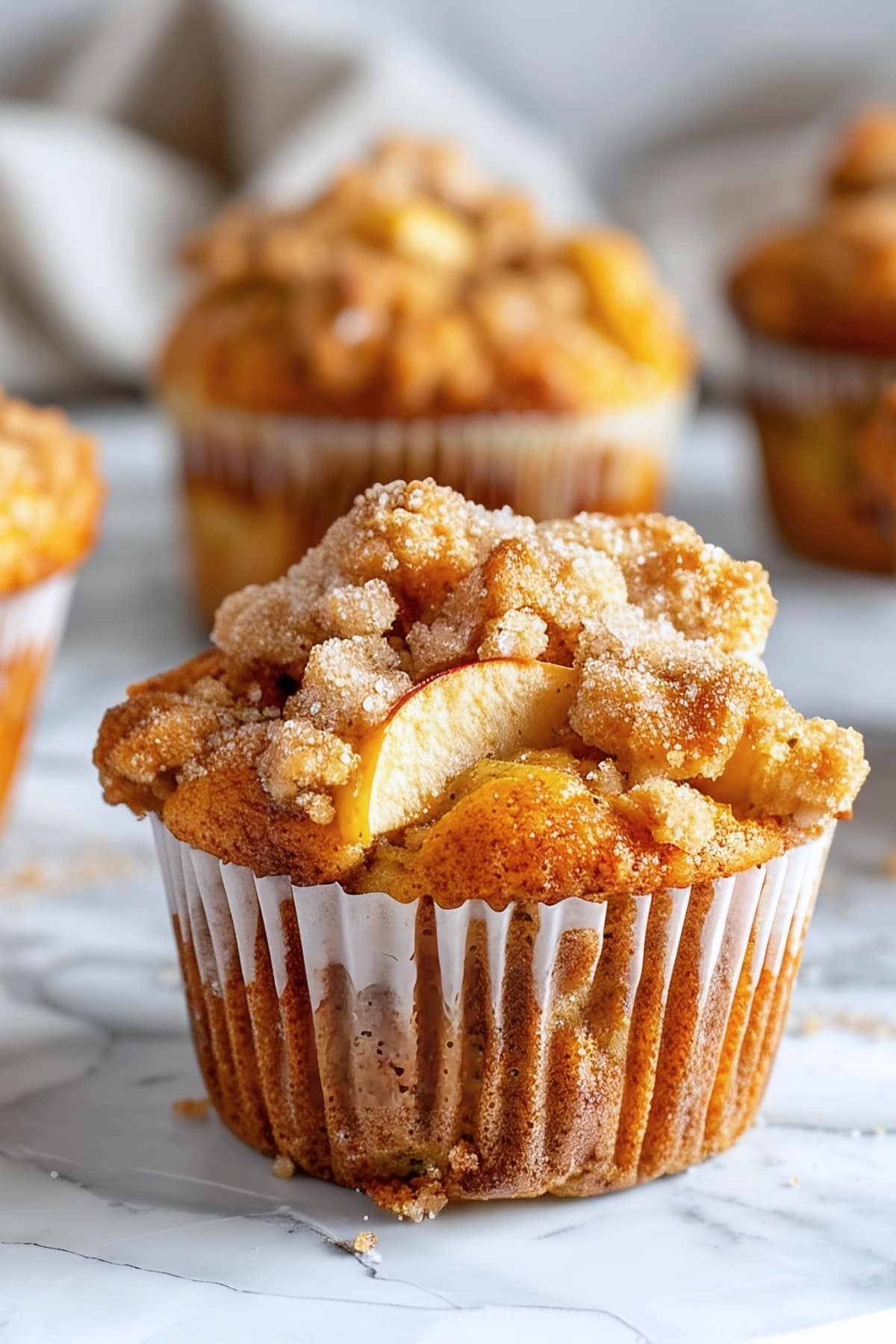 Apple muffins with crumb toppings on a marble surface