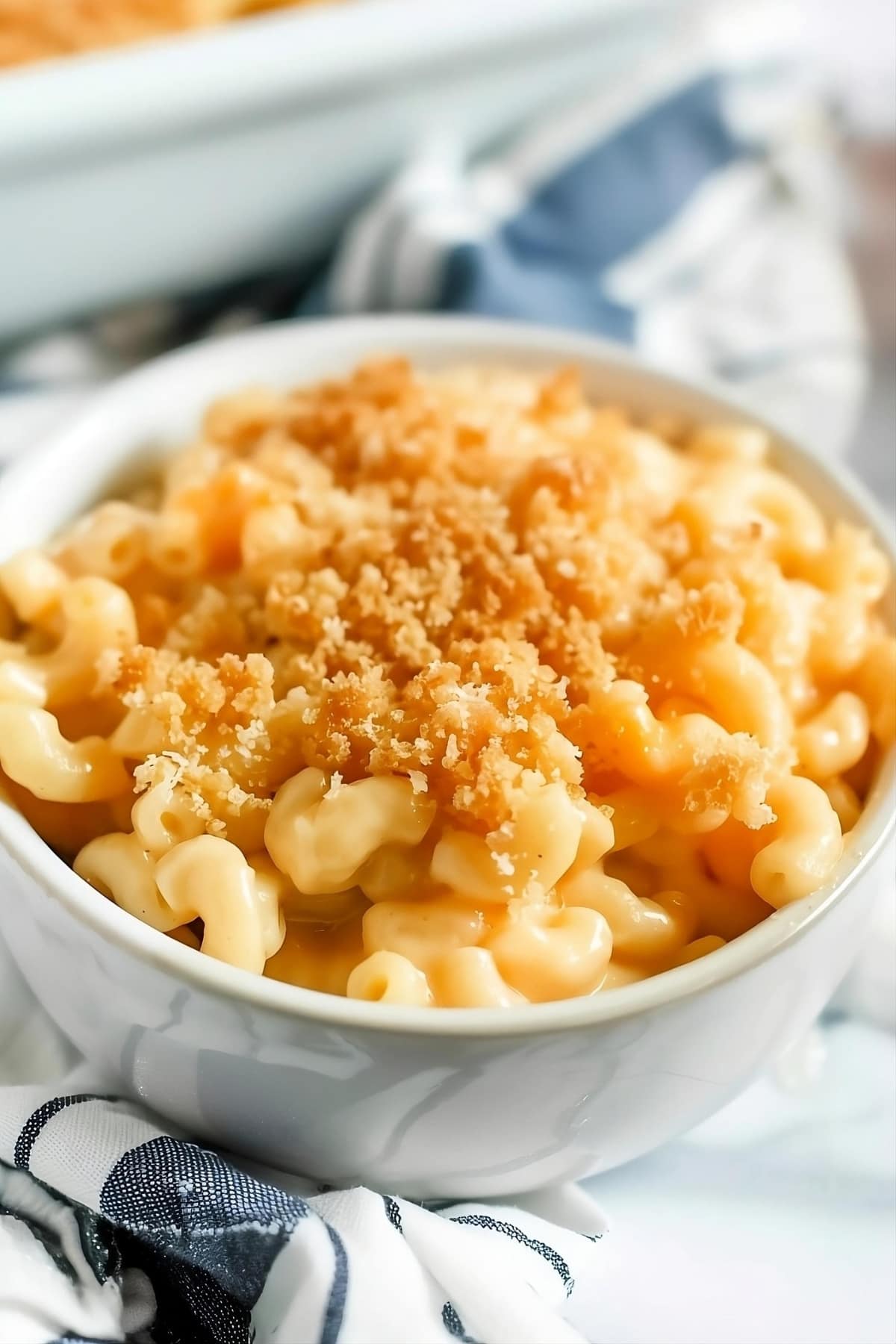 Cheesy mac and cheese in a white bowl topped with crushed Ritz crackers.